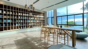 Une bibliothèque moderne dotée d’une grande étagère, d’un coin repas et offrant une vue sur la mer.