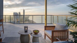 Un balcon donnant sur le panorama urbain, une table avec une bougie et des meubles en osier.