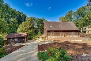 A rustic cabin with a covered porch, a small shed, and a well-maintained garden.