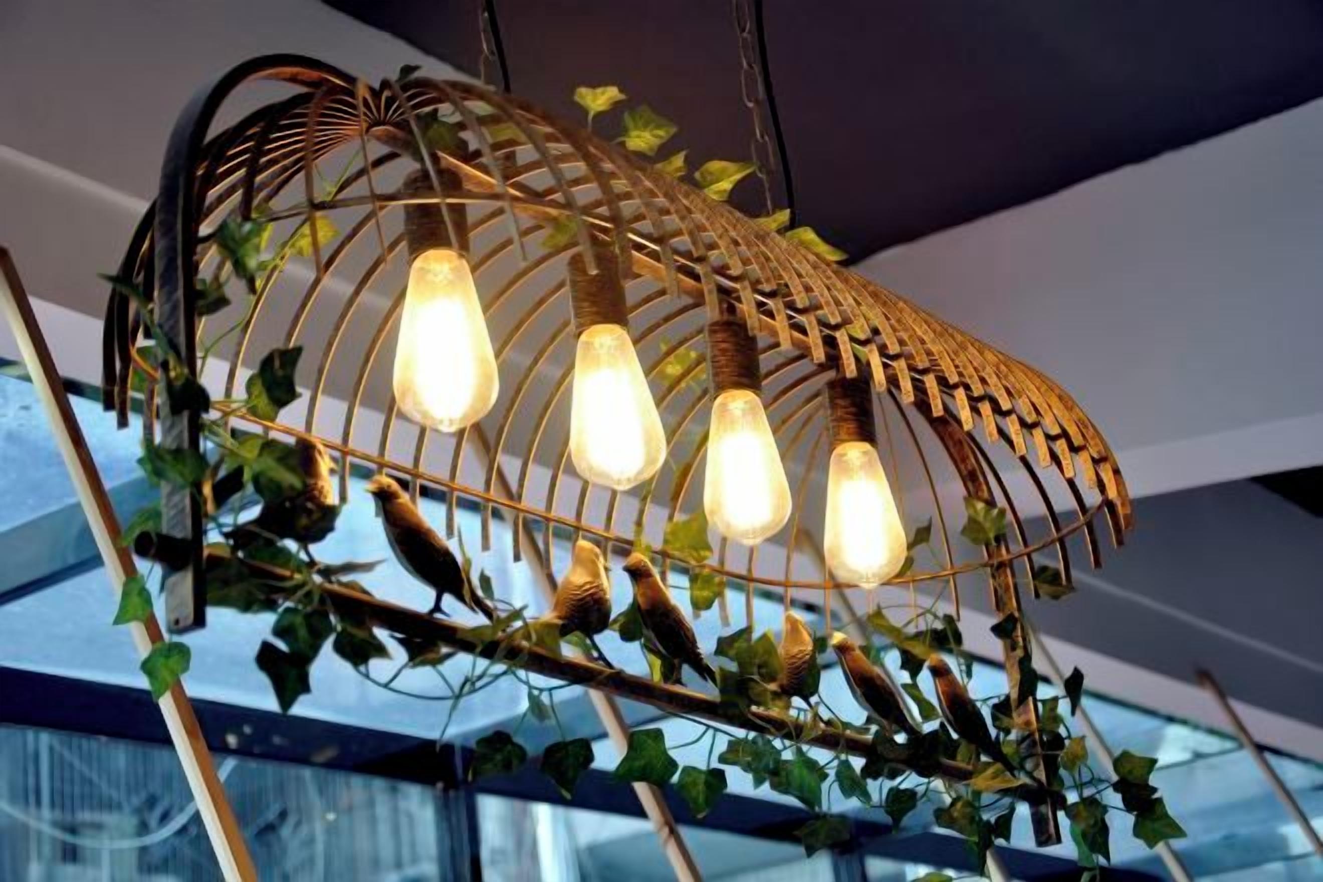 A hanging light fixture with multiple bulbs and birds perched on it.