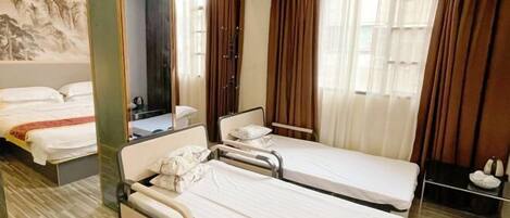Habitación de hotel con dos camas individuales, un espejo grande, baño con ducha y un cuadro en la pared.