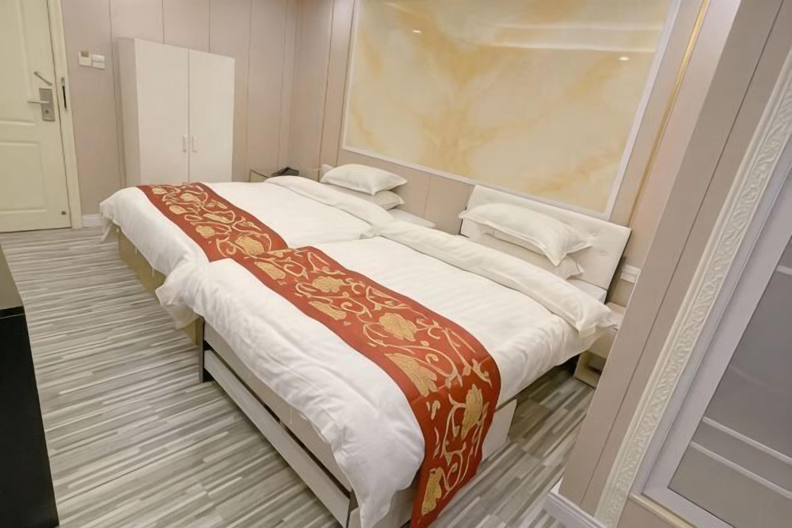 A hotel room with a bed, a wardrobe, a large mirror, and a carpeted floor.