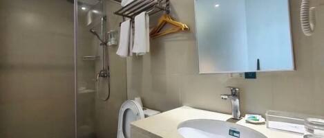 A bathroom with a glass shower enclosure, a toilet, a sink with a mirror above it, and a towel rack with hangers.