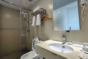 A bathroom with a glass shower enclosure, a toilet, a sink with a mirror above it, and a towel rack with hangers. - Yiru Express Apartment Hotel（Shantou's long corridor on the seaside) (Shantou)