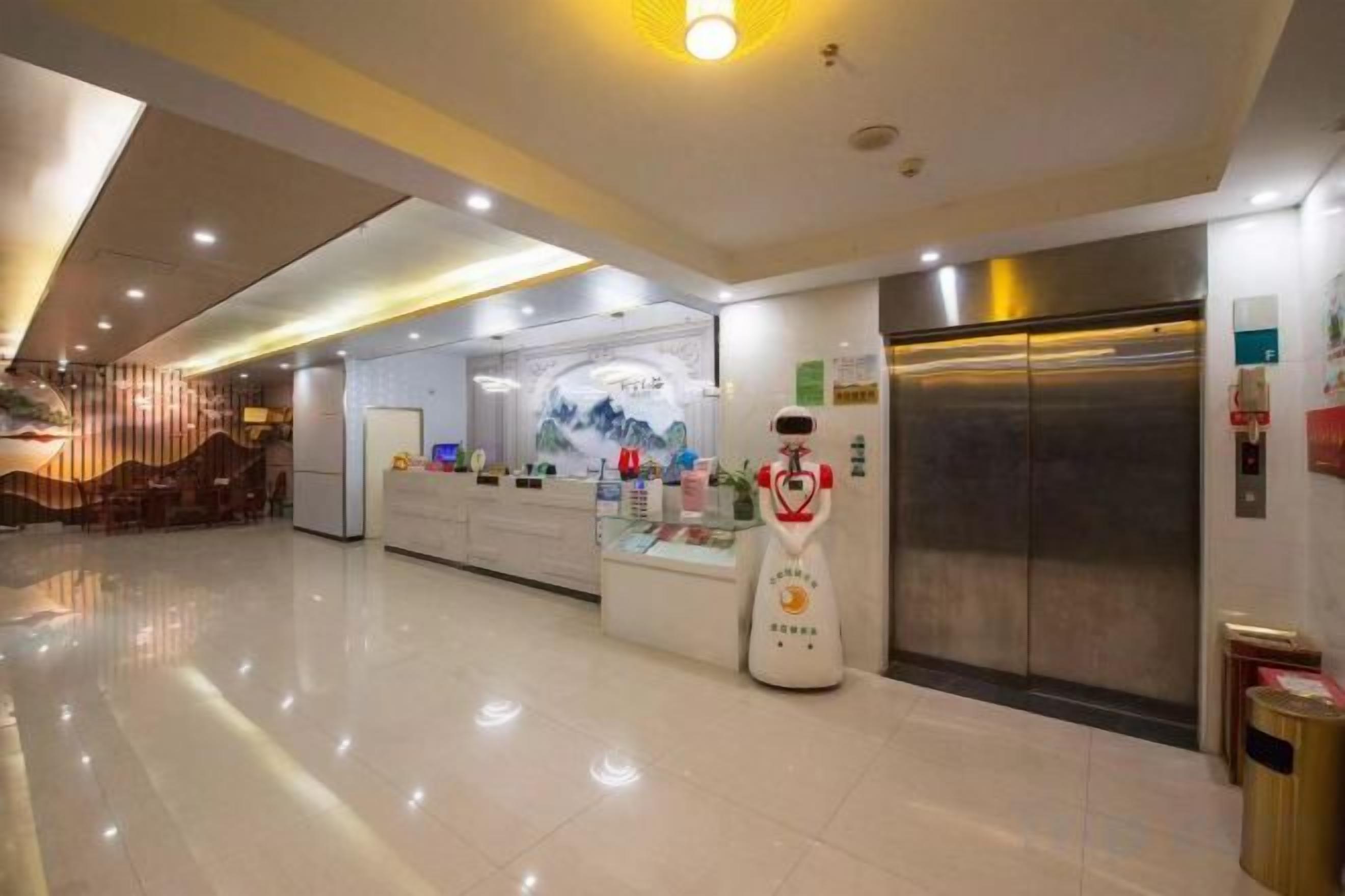 A hotel lobby with a reception desk, a vending machine, and a large elevator.