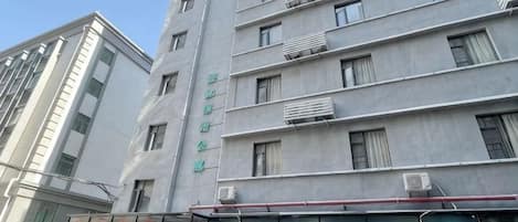 Un edificio de varios pisos con estilo arquitectónico moderno, que cuenta con una serie de ventanas y unidades de aire acondicionado en la fachada.