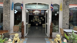 Fachada de hotel de piedra, puerta de vidrio y suelo de baldosas.