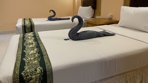 Dos camas con sábanas blancas y toallas decoradas con forma de cisne.