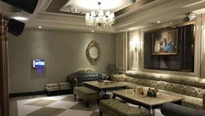 A luxurious room with a checkered floor, a chandelier, a large mirror, a painting, and a seating area with a table and ottomans. - Fulin Hotel (Huilai)