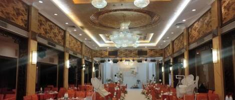 A banquet hall with rows of tables, chairs, and a central aisle.