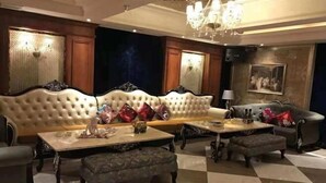 A luxurious living room with a large sofa, a coffee table, and a side table. There is a chandelier hanging from the ceiling. - Fulin Hotel (Huilai)