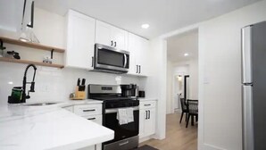 Una cocina moderna con gabinetes blancos, un refrigerador de acero inoxidable y un microondas integrado.