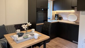 Una cocina compacta con armarios oscuros, horno empotrado, cafetera y lavabo.
