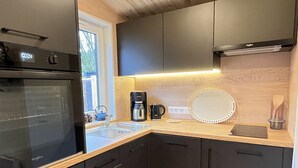 Una cocina moderna con horno empotrado, cafetera y un espejo redondo en la encimera.