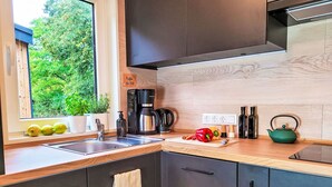 Une cuisine moderne avec une fenêtre, une machine à café, une bouilloire et une planche à découper avec des légumes.
