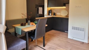 Une cuisine de taille réduite, avec des meubles de couleur sombre, un plan de travail en bois et un réfrigérateur blanc.