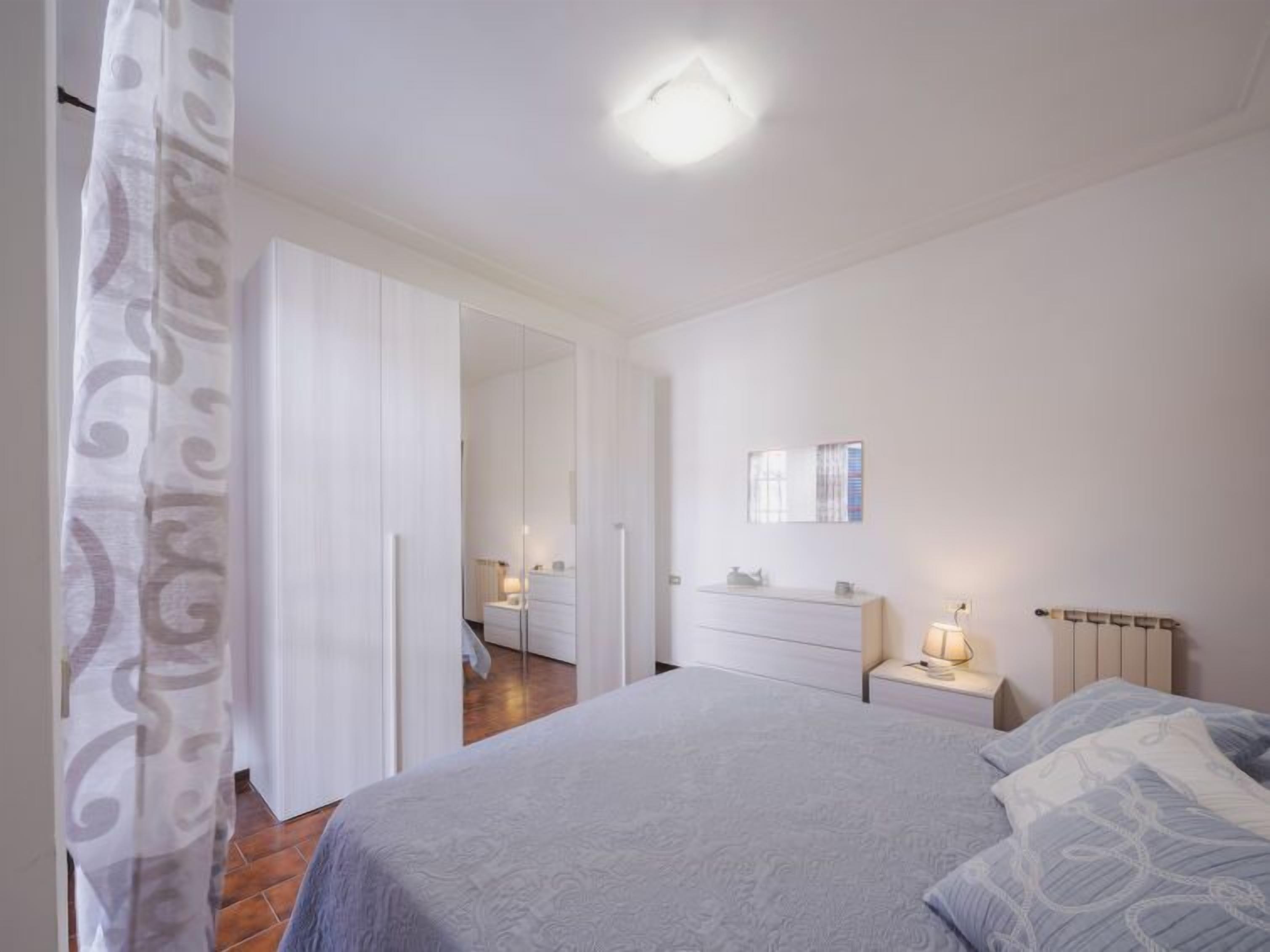 A bedroom with a bed, a nightstand, a dresser, and a mirror on the wall.