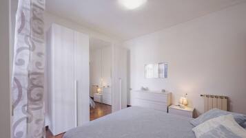 A bedroom with a bed, a nightstand, a dresser, and a mirror on the wall.