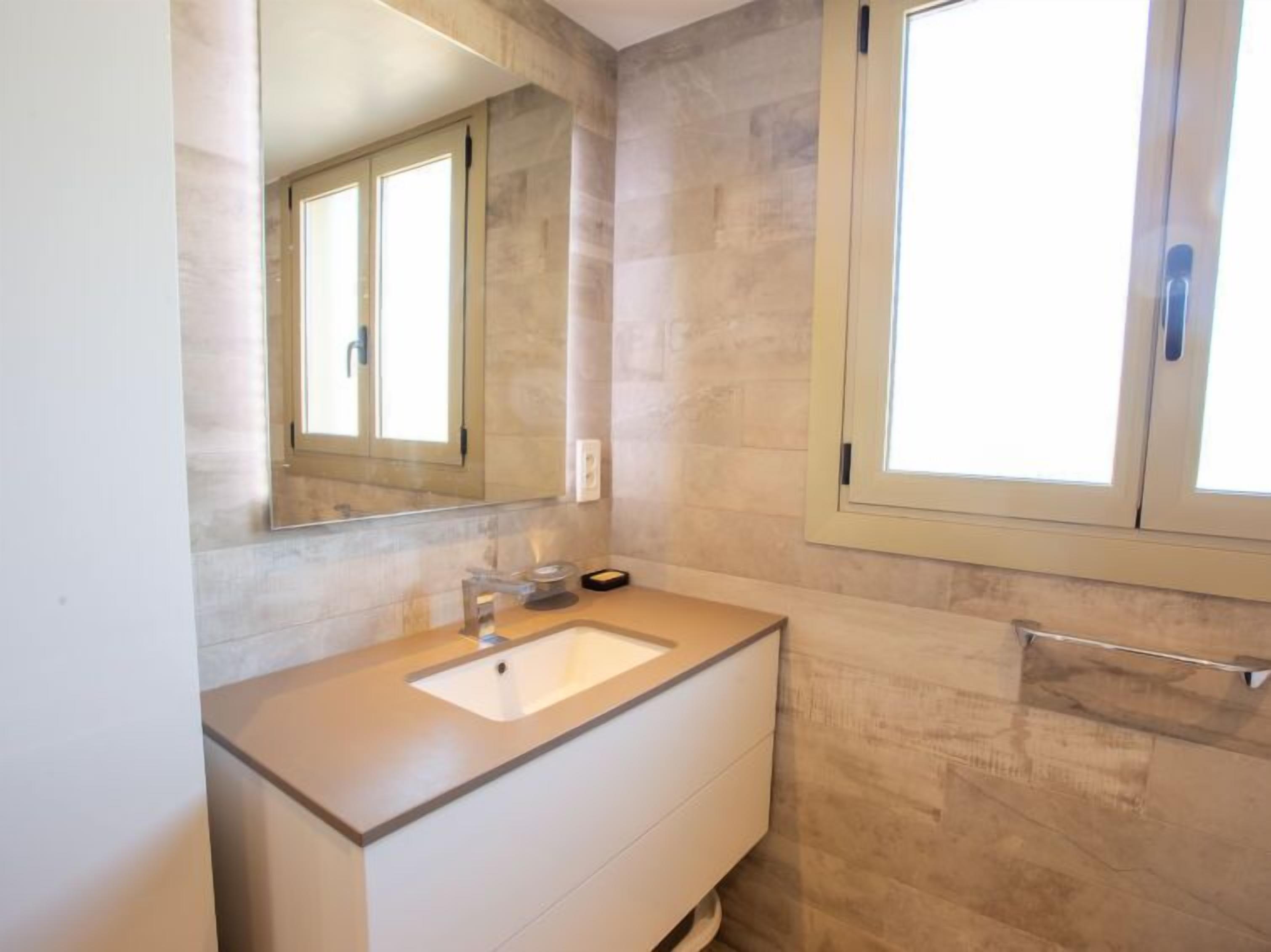 Un bagno moderno con uno specchio grande, un lavandino e una finestra.