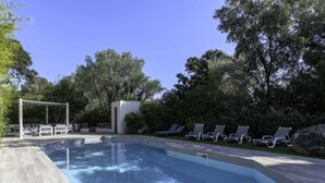 A rectangular swimming pool with a wooden deck, surrounded by lounge chairs and a pergola. - Villa Romana by Interhome (Porto Vecchio)