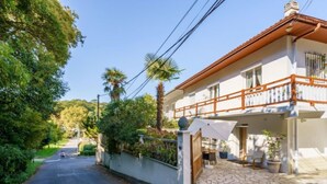 A two-story house with a stone-paved patio, a wooden fence, and a balcony. - Chiquito by Interhome (Biarritz)