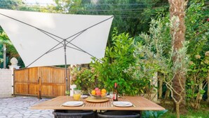 An outdoor patio with a wooden table set for two, surrounded by stone flooring and black wicker chairs. - Chiquito by Interhome (Biarritz)