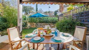 A wooden deck with a round table set for dining, surrounded by chairs. - Le Laurier by Interhome (Sainte Maxime)