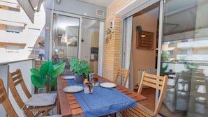 A balcony with a wooden table set for two, surrounded by chairs, and a potted plant. - Apartment Silves by Interhome (Tossa de Mar)