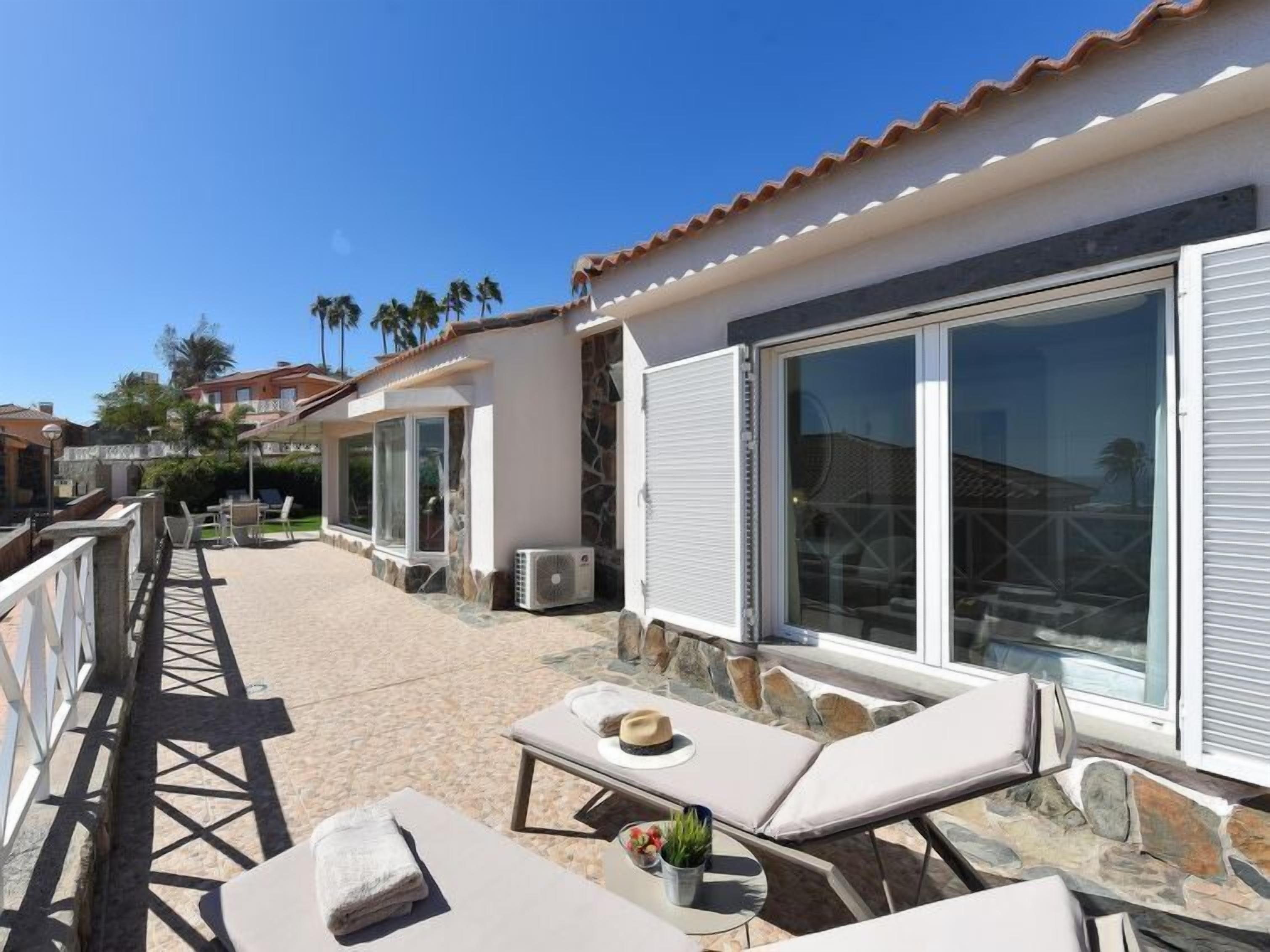 Um resort com área de piscina, espreguiçadeiras e vista para o oceano.