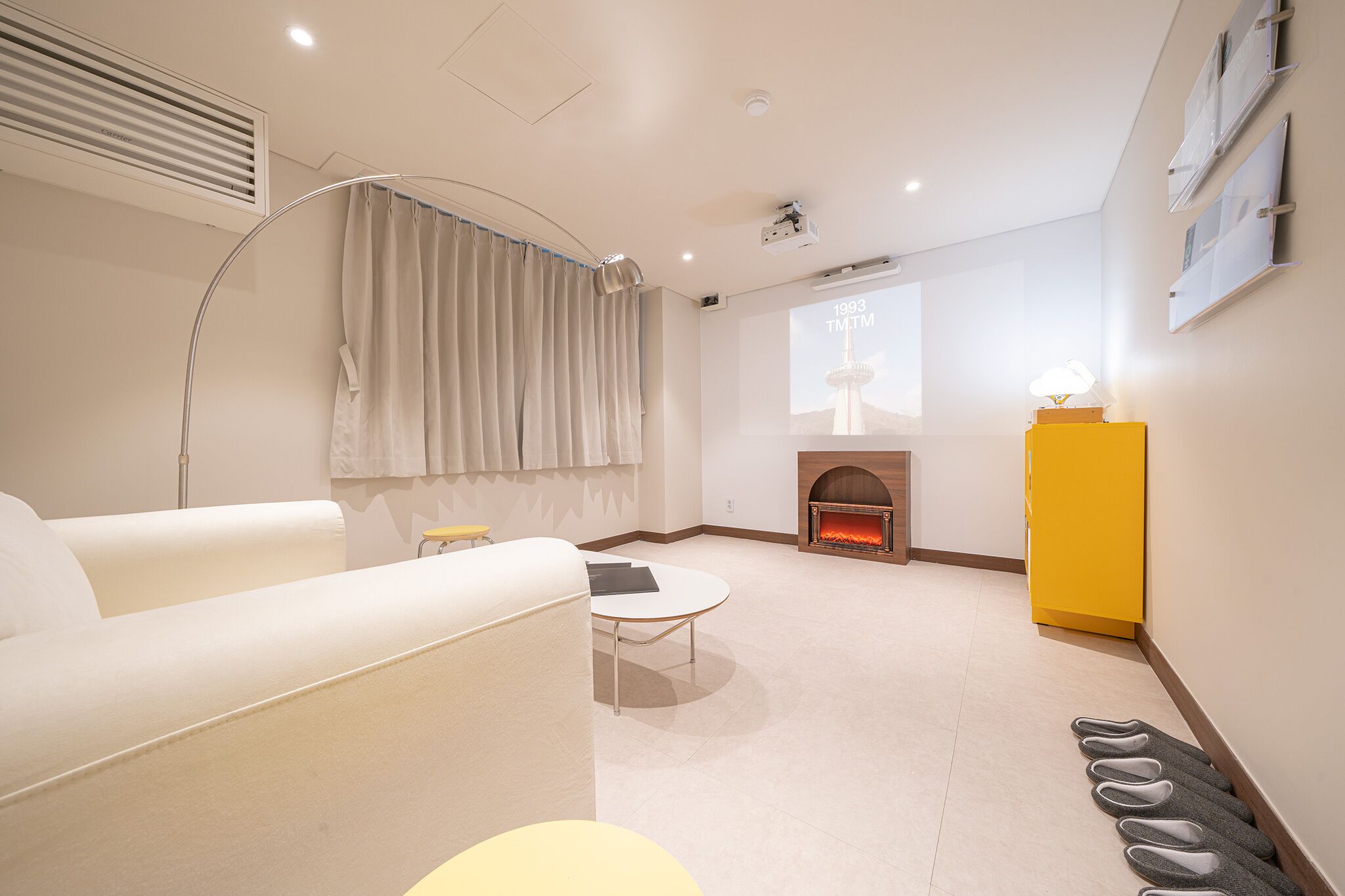 Uma sala de estar moderna com um sofá, uma mesinha, uma lareira e um par de chinelos no chão.