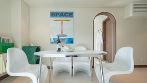 Een moderne eethoek met een witte tafel en stoelen, een poster aan de muur en een groene kast.