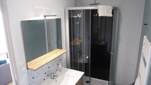 Un bagno moderno con cabina doccia in vetro, mobile lavabo in legno e lavandino bianco.