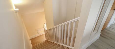 A staircase with a white railing and beige carpet.