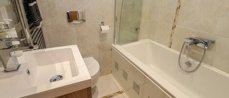 A bathroom with a white sink, toilet, and glass-enclosed shower.