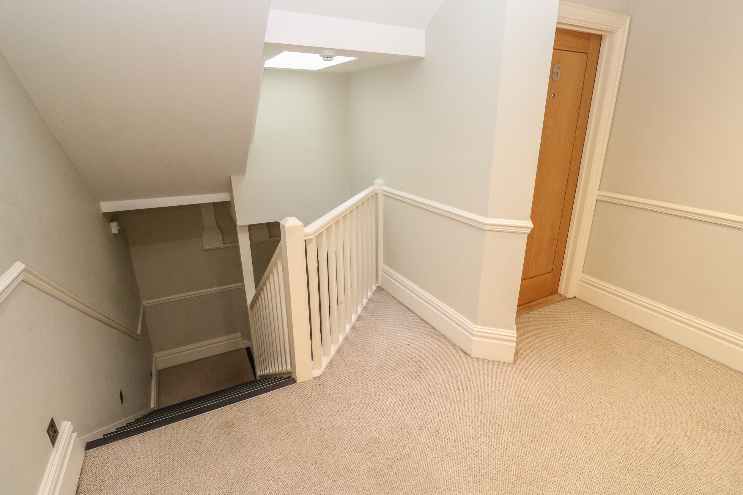 A staircase with white railings leading to a landing.
