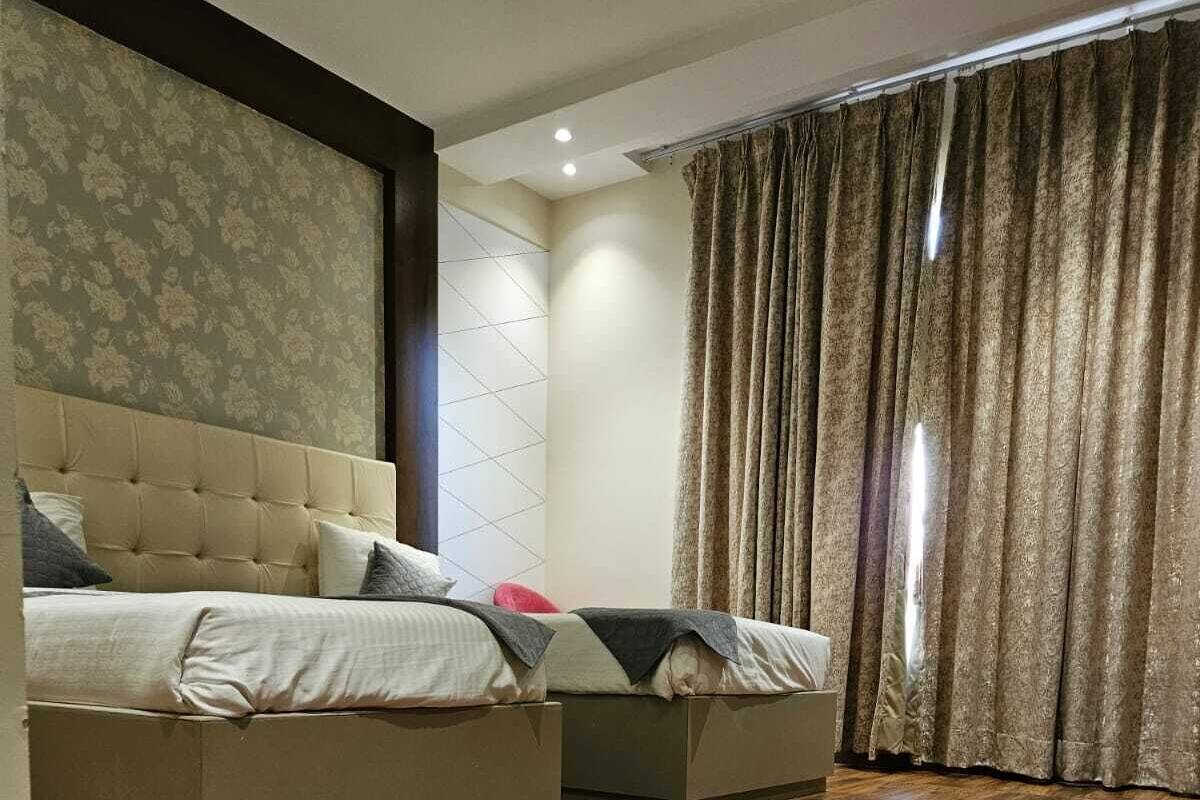 Quarto com uma cama grande, uma cama menor e uma janela ampla com cortinas.
