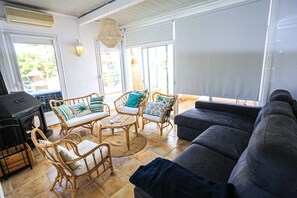 Sala de estar com móveis de vime, um sofá e uma churrasqueira.