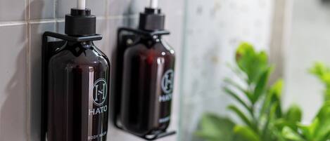 Two body wash dispensers mounted on a tiled wall.