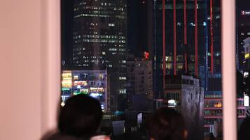 Ein Blick auf eine beleuchtete Stadtlandschaft bei Nacht mit Lichtern und vertikalen Lichtstreifen.