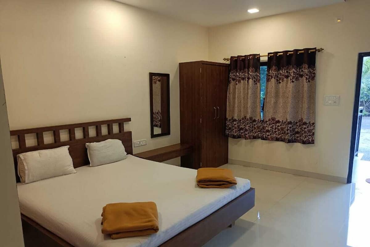 Quarto com uma cama grande, um guarda-roupa e uma janela com cortinas.