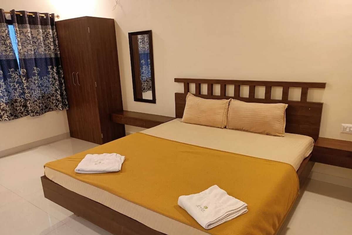 Quarto de hotel com cama, guarda-roupa, mesa de cabeceira e um quadro na parede.