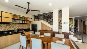 Eine moderne Küche mit Essbereich, Holzschränken und einem schwarzen Kühlschrank.