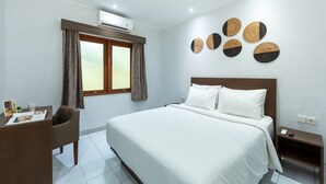 Ein Hotelzimmer mit einem großen Bett, einem Schreibtisch mit Stuhl, einem Fenster mit Vorhängen und Wandbildern.