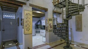 Eine Wendeltreppe in einer Diele mit einer Tür, eine Küche im Hintergrund und einer Wand mit Muster.