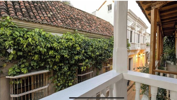 Ein Balkon mit Blick auf ein Gebäude mit einem Ziegeldach und einem weißen Geländer.