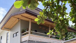 A two-story building with a balcony, multiple windows, and potted plants around the entrance. - Marelocca Beach House  (Calatagan)