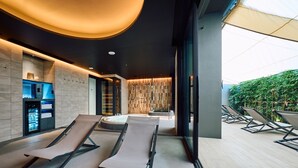 A modern spa area with lounge chairs, a heated floor, a sauna, and a wall with a vertical garden. - FAV LUX NAGASAKI (Nagasaki)