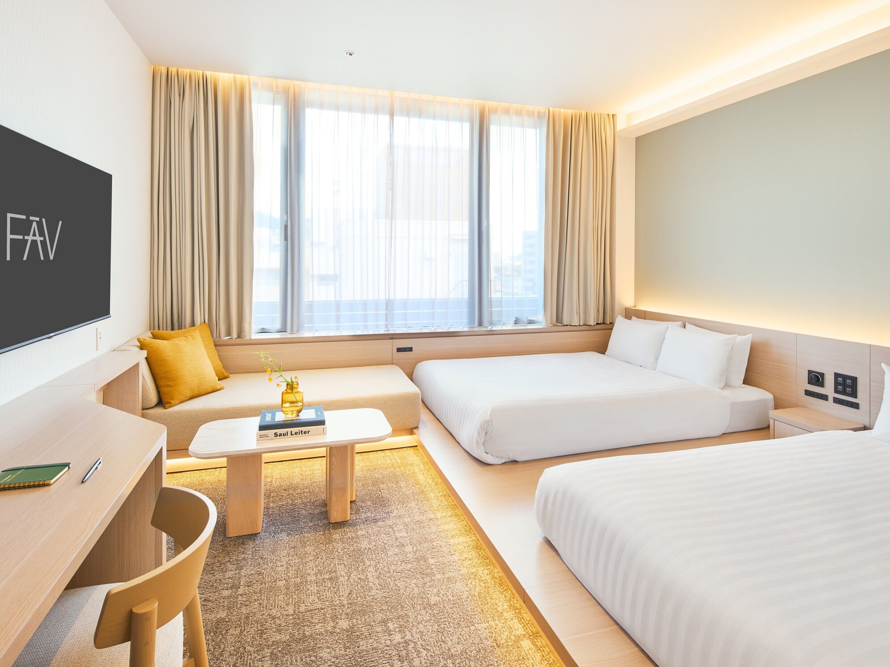 A hotel room with a bed, a sofa, a desk, and a TV.