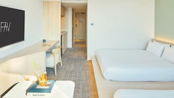 A hotel room with a bed, a desk with a chair, a television, and a small table with a book and a vase.
