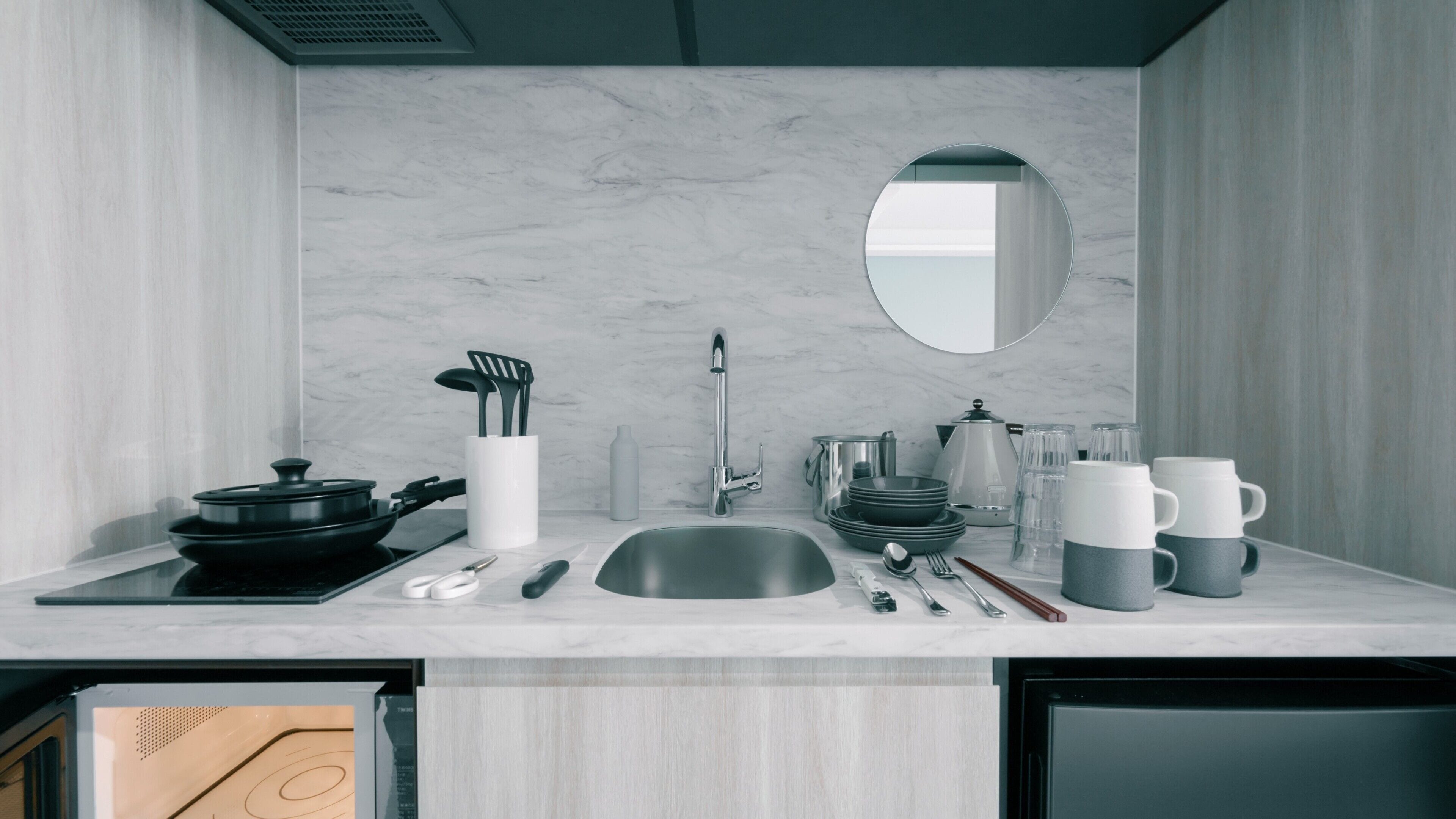 A modern kitchen with a sink, stove, and various utensils.